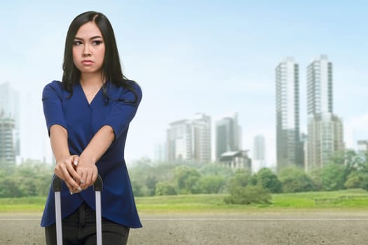 Beautiful asian tourist holding suitcase handle with cityscape background