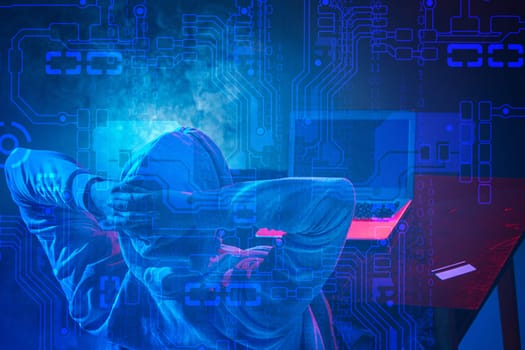 Hooded computer hacker stealing information with laptop. Concept of threat