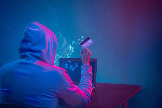 Hooded computer hacker stealing information with laptop. Concept of threat