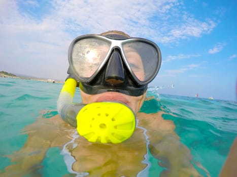 Portrait of a yound woman floating and wearing snorkeling gear in the clean blue sea of Protaras, Cyprus. Close up view of tube, mask, bikini of free diver overthe surface of the water.