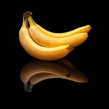 Bunch of ripe bananas with real reflection on a black background isolated