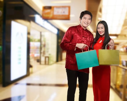 Asian couple holding shopping bag with mall background