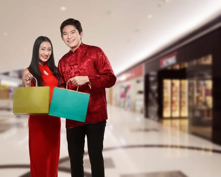 Asian couple holding shopping bag with mall background