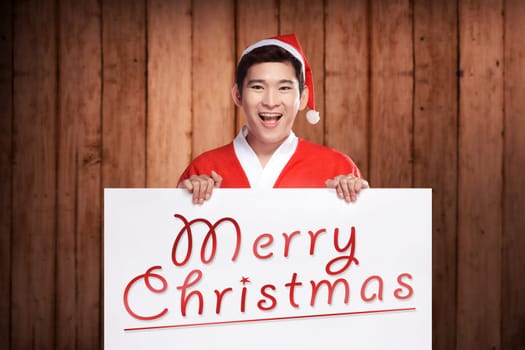 Asian man wearing santa claus costume holding banner with merry christmas writing