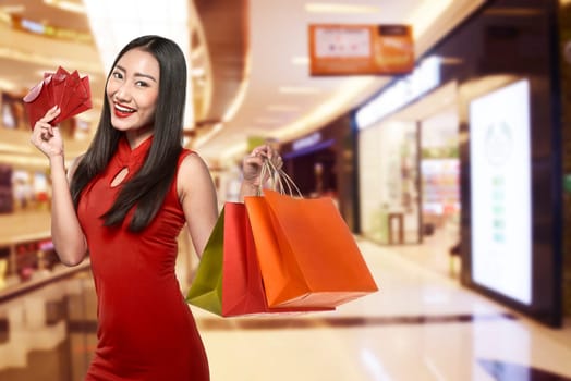 Chinese woman wearing traditional clothes holding shopping bag with mall background