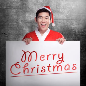 Asian man wearing santa claus costume holding banner with merry christmas writing