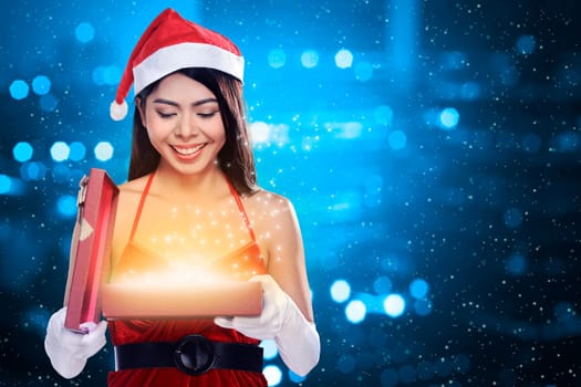 Beautiful smiling christmas santa woman wearing santa claus costume opening gift box
