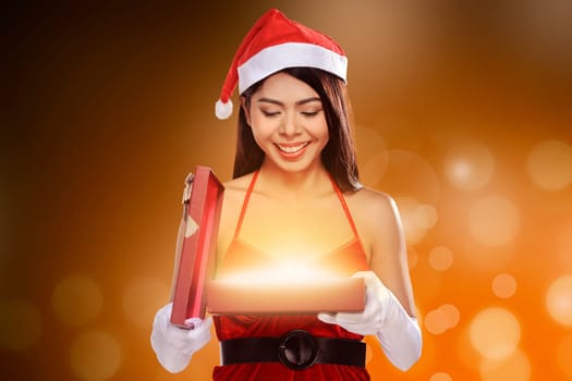 Beautiful smiling christmas santa woman wearing santa claus costume opening gift box