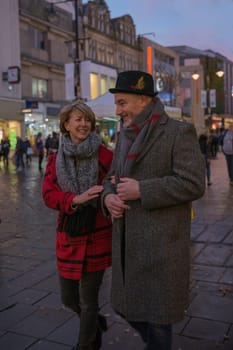 Mature couple are enjoying some winter shopping on an evening at christmas time.