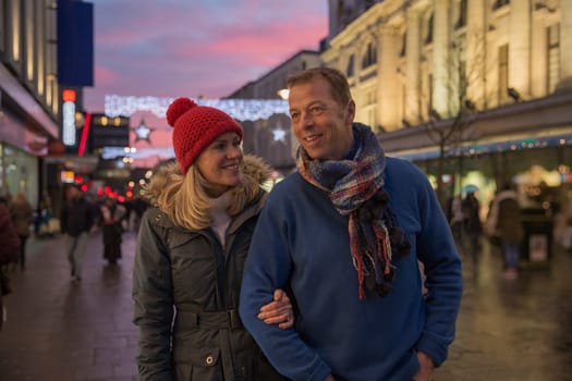 Mature couple are enjoying an evening stroll through town at Christmas time.