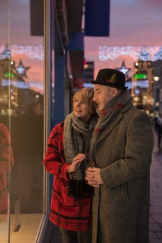 Mature couple are enjoying some winter shopping on an evening at christmas time.