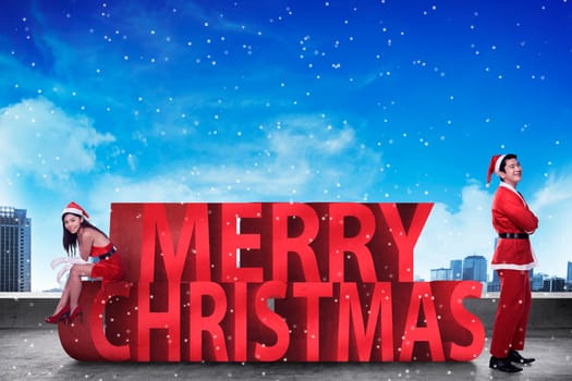 Asian couple in santa claus costume posing on merry christmas text. Christmas couple concept