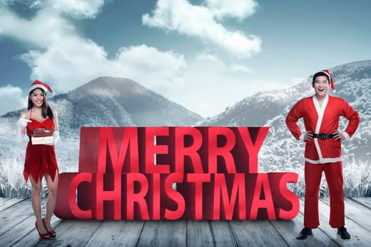 Asian couple in santa claus costume posing on merry christmas text. Christmas couple concept