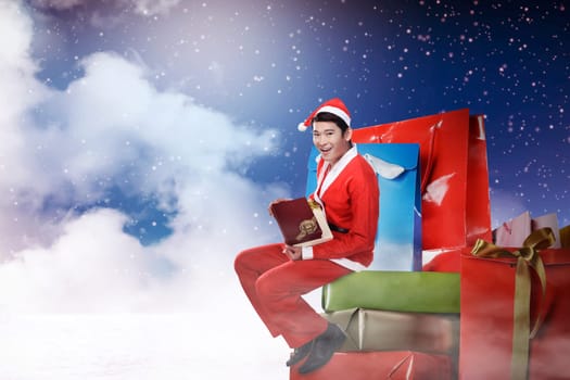 Young asian man wearing santa claus costume sit on the big present box