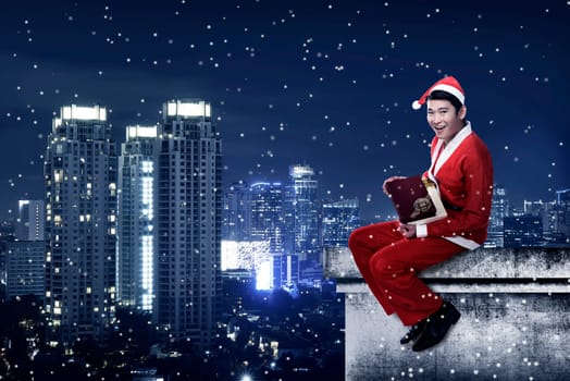 Asian man wearing santa claus costume sit on the rooftop. Christmas present