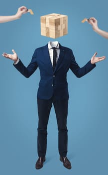 Businessman with wooden game box instead of head on gray studio background.