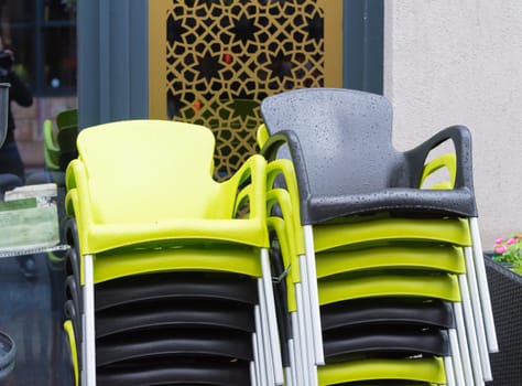 pilud up green and black chairs on a rainy day