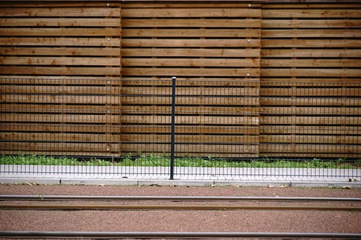 A newly built tram track with a fence and a wooden board privacy screen at the edge.