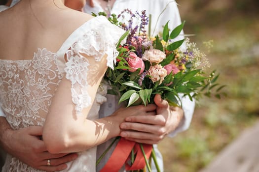 Wedding decoration in the style of boho, floral arrangement, decorated table in the garden. Against the background of the bride and groom embracing.