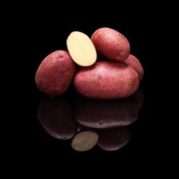 Pile of red potatoes isolated on a black glossy background with real reflection