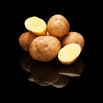 Pile of yellow potatoes isolated on a black glossy background with real reflection
