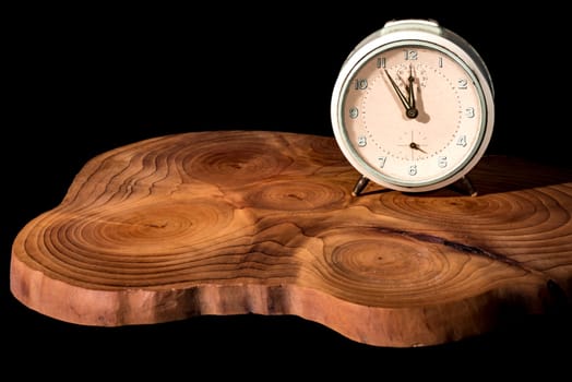 Old alarm clock five to twelve on a wooden board