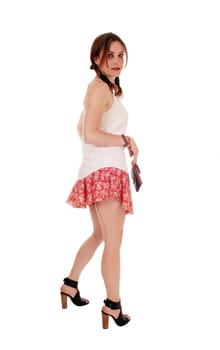A beautiful young woman standing in profile, looking back, with a purse,.standing isolated for over white background.