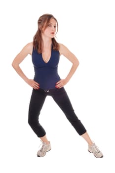A beautiful young woman in an exercising outfit standing over white.background with her hands on her hips, looking serious.