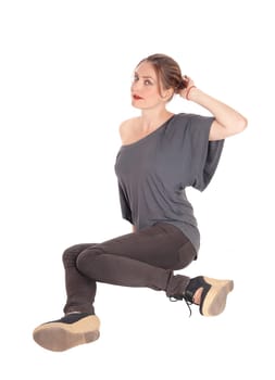 A beautiful young woman in jeans and brunette hair sitting .on the floor and looking up, isolated for white background.