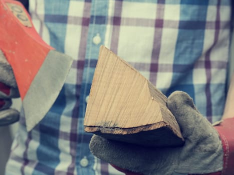 Young man holding an axe and fire wood, selective focus on wood, retro film stylized, alternative energy concept