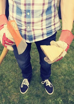 Young man holding an axe and fire wood, selective focus on wood, retro film stylized, alternative energy concept