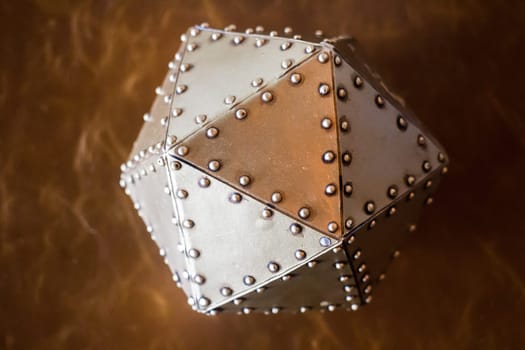 Metal hexagon ball on brown leather background, stock photo