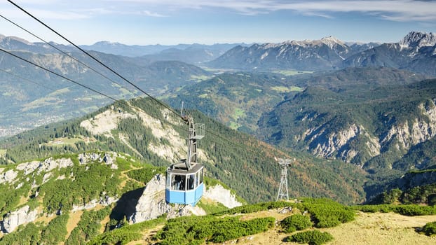 Aerial cableway gondola lifts tourists to top of Alpspitze mountain in Bavarian Alps