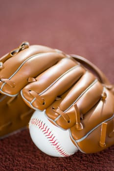 Baseball glove and ball on baseball field.