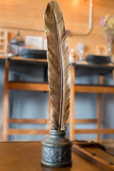Metal bird feather on leather background, stock photo