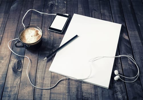 Photo of blank stationery set. Letterhead, letterhead, coffee cup, smartphone, pencil and headphones. Paperwork template for designers. Responsive design mockup on vintage wood table background.