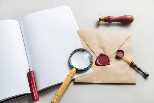 Vintage postal stationery set on paper background. Photo of blank book, envelope, magnifier, seal, stamp and spoon. Responsive design template for placing your design. Top view.