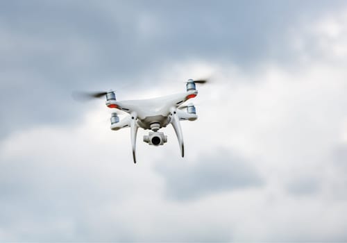 Quadrocopter drone hovers in the sky. Drone quad copter. Flying unmanned camera.