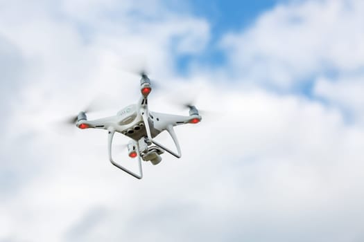 Flying quadrocopter drone against the sky with clouds. Quad copter drone. Unmanned camera.