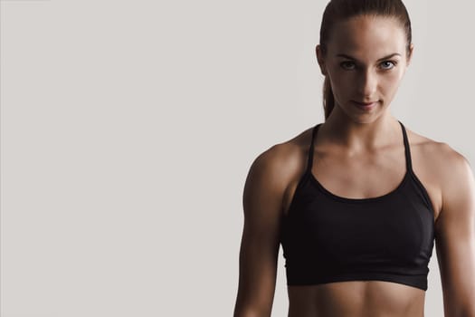 Portrait of a fitness woman posing against a gray background