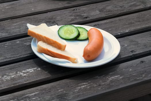 Bockwurst,Wienerwürstchen or Frankfurther wurst with toast and cucumbers on a white plate.
