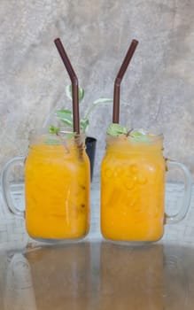 Orange juice with ice cube on glass table, stock photo