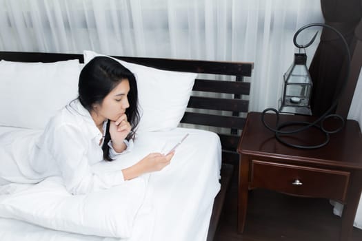Young Asian woman playing puppy doll on the bed in morning bedroom, alone and lonely