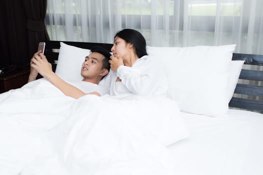 Couple using smartphone on the bed in the morning, smile