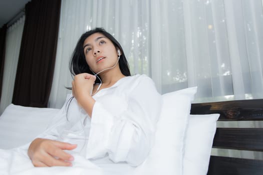 Young Asian woman playing puppy doll on the bed in morning bedroom, alone and lonely