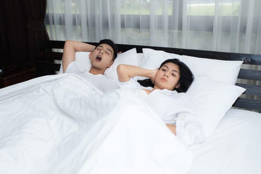 Couple using smartphone on the bed in the morning, smile