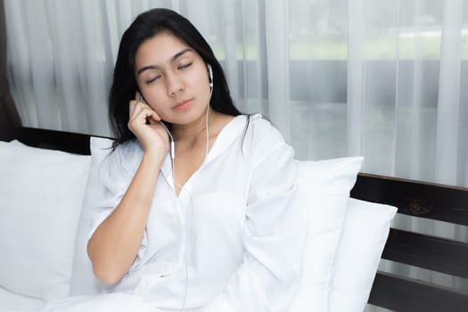 Young Asian woman playing puppy doll on the bed in morning bedroom, alone and lonely