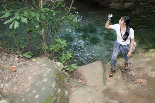 Young asian woman taking photos in autumn forest with camera