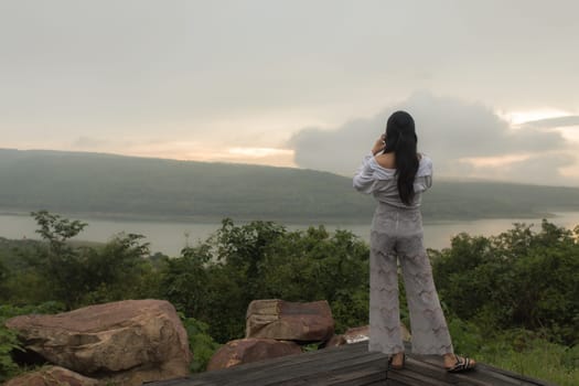 Young asian woman hiker stops to tie her shoe on a summer hiking trail in forest.