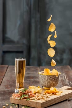 The glass of Beer and potato chips, pistachios isolated on a white